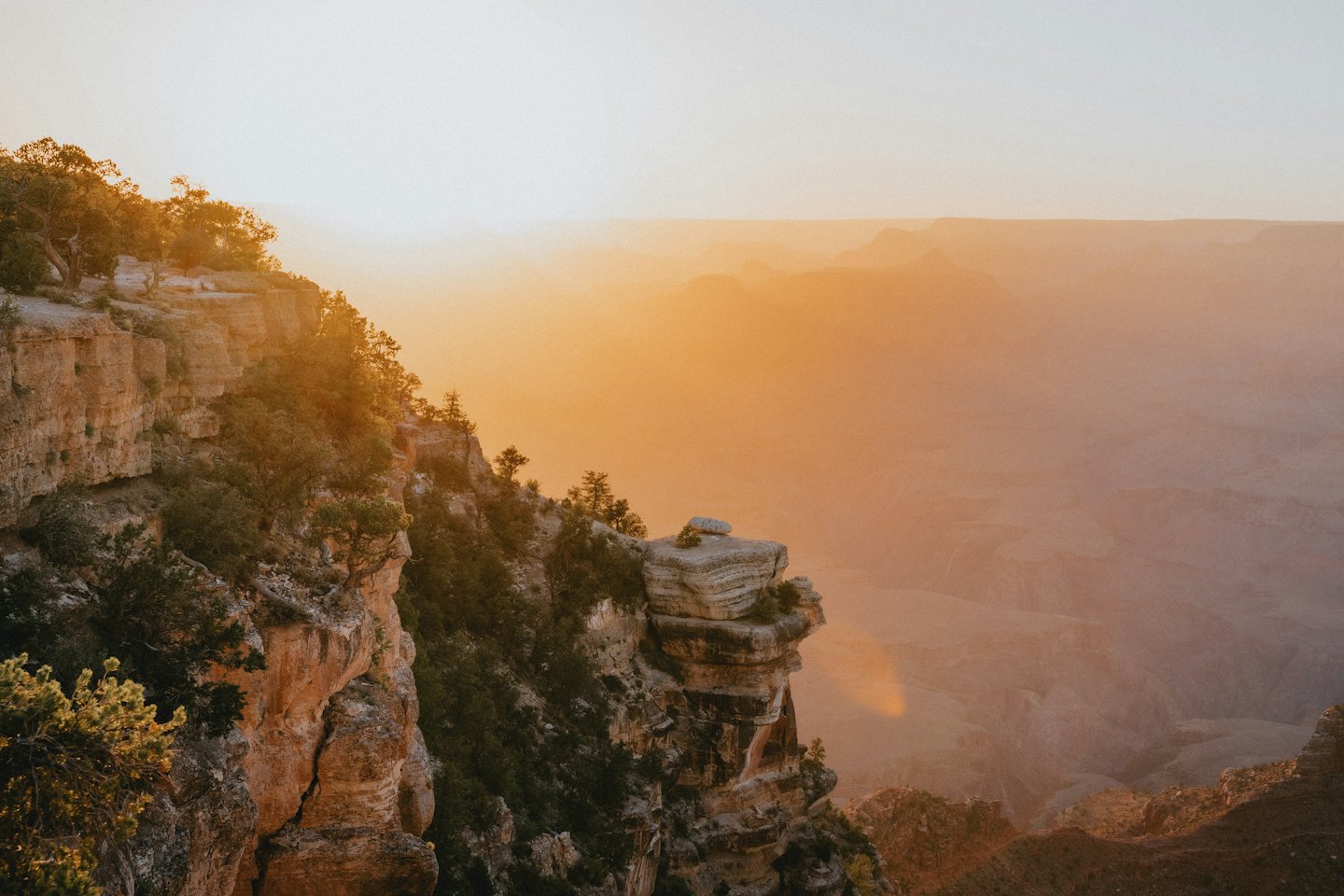 Vast canyon landscape with orange cliffs at sunset.