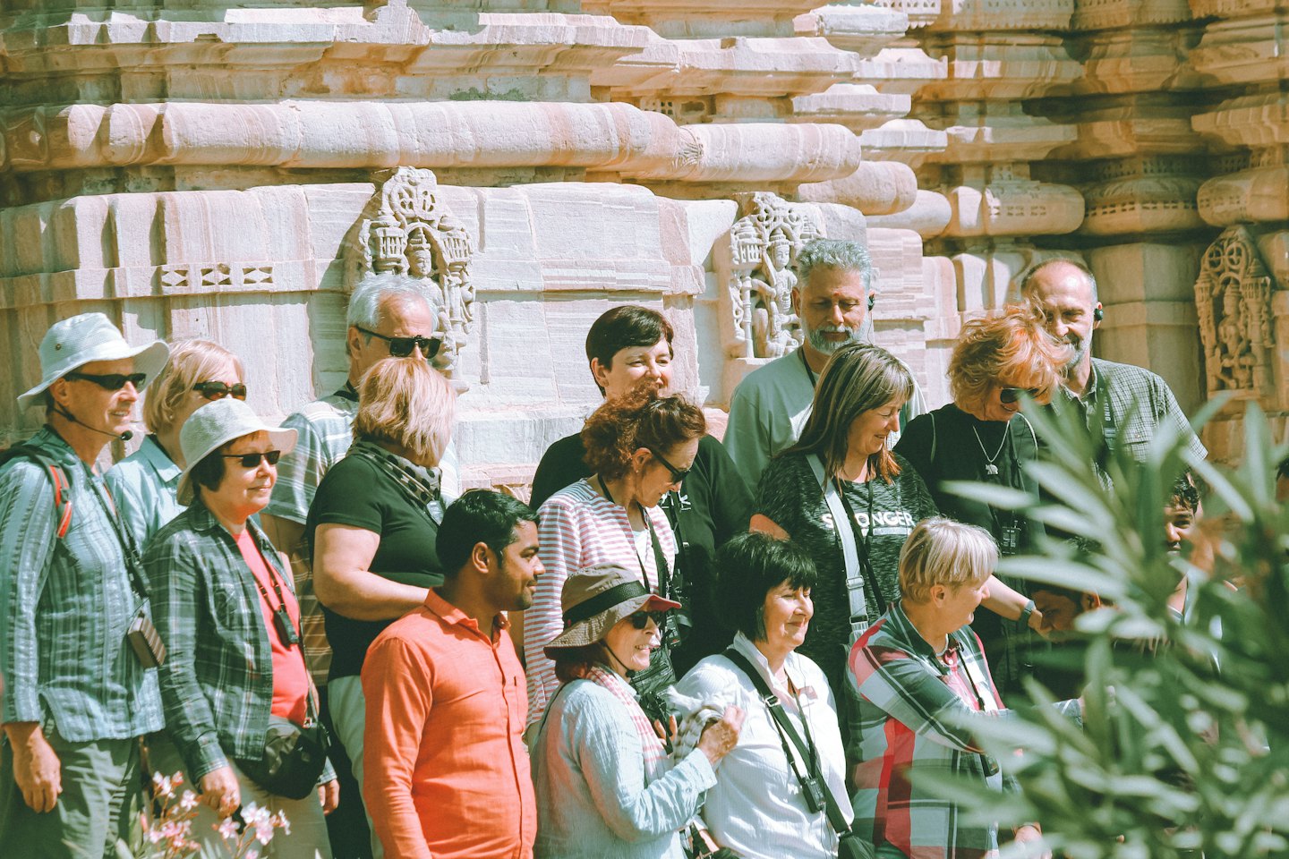 Tourists listen to a guide in front of a carved stone building.