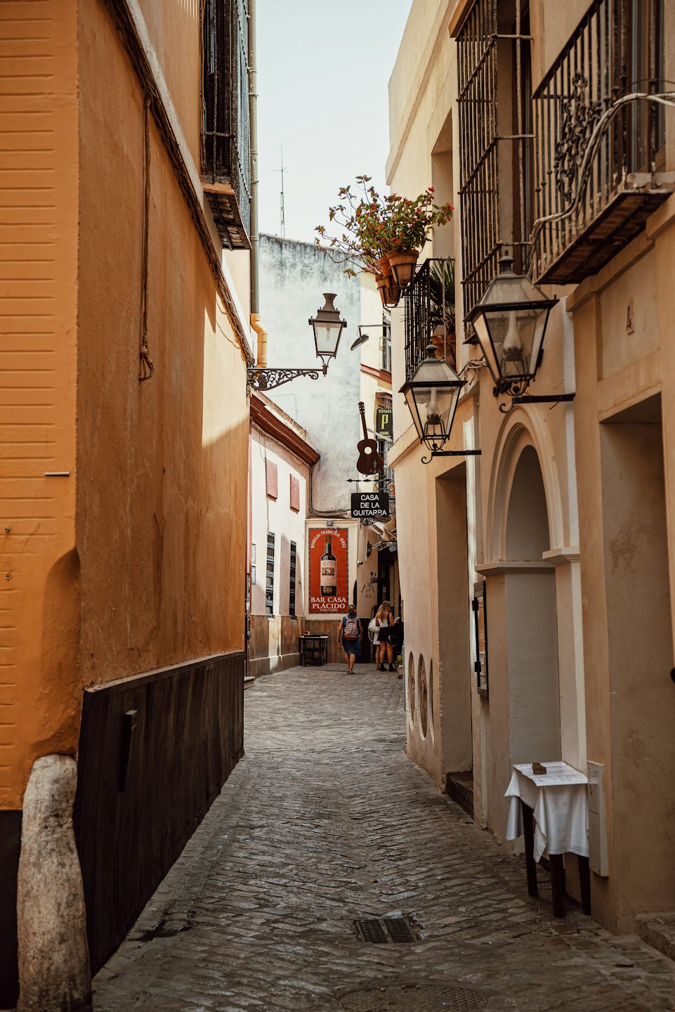 Cobbled alleyway in old European city with ochre buildings and balconies.
