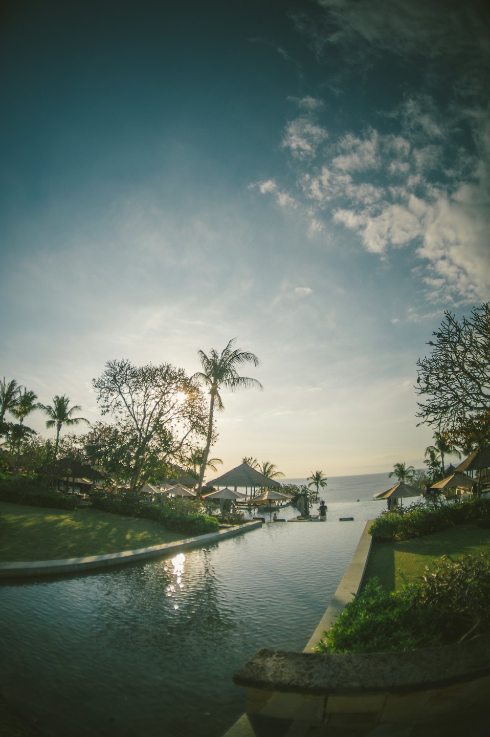 Tropical resort infinity pool overlooking the ocean at sunset.