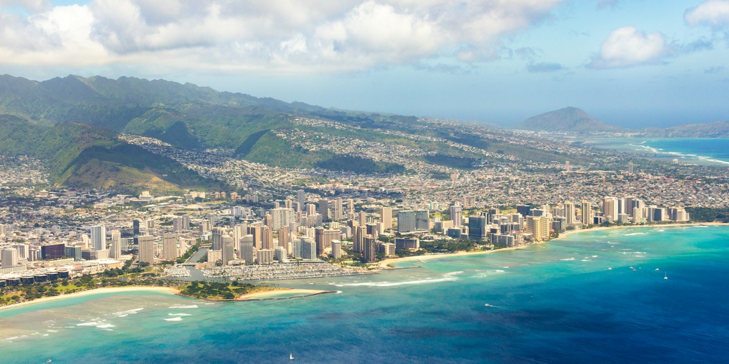 Aerial view of a coastal city with high-rises on a sandy beach and turquoise ocean.